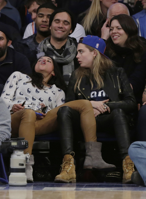 FILE - In this Tuesday Jan. 7, 2014 file photo Michelle Rodriguez, left, blows vapor from an electronic cigarette as Cara Delevingne watches during the second half of an NBA basketball game between the New York Knicks and the Detroit Pistons in New York. Under a New York City law taking effect Tuesday, April 29, 2014, vaporizing devices will be treated the same as a tobacco-based cigarette. The New York ban, along with similar measures in Chicago and Los Angeles and federal regulations proposed last week, are again igniting debate among public health officials, the e-cigarette industry and users lon the future of the popular devices. (AP Photo/Frank Franklin II, File)