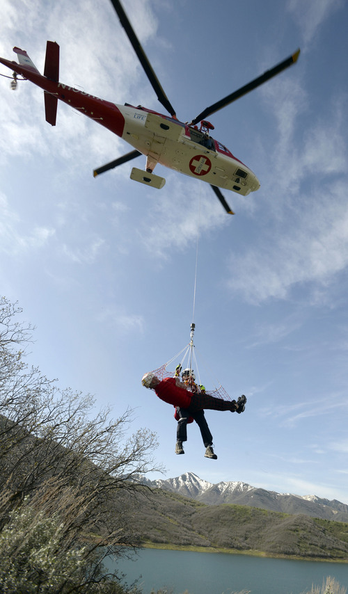Al Hartmann  |  The Salt Lake Tribune
Curtis Andersen, a flight paramedic with Life Flight, rises on a hoist line with Utah County Search and Rescue's Toby Norton, (playing an injured person) in a rescue net, during a practice drill at Little Dell Reservoir Monday May 5, 2014. Paramedics and Life Flight crews practiced a series of "live" hoist rescues to prepare for the upcoming summer season. The hoist rescues covered a number of scenarios in which injured recreationalists are injured or stranded and need to be airlifted to safety. Intermountain Life Flight is the first and only civilian air ambulance in the nation equipped and licensed to perform hoist rescues. A paramedic is lowered to an injured or stranded person on a specially designed hoist attached to the helicopter. Life Flight operates Agusta twin-engine helicopters equipped for hoist operations that are well suited for high-altitude performance.