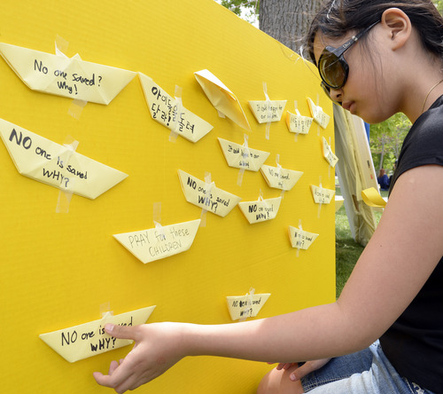 Rick Egan  |  The Salt Lake Tribune

April Kim, 10, tapes paper boats to a sign in honor of the victims of the South Korea ferry disaster, during a rally at Liberty Park, Sunday, May 18, 2014.  The rally was held to remember, honor and pray for victims and families of the South Korea ferry disaster that killed more than 300 people, mostly high school students, on April 26. It was organized by Korean ex-patriots living in Utah as part of a 50-state rally organized by Missy USA, a social website catering to Korean and Korean American women in the U.S.