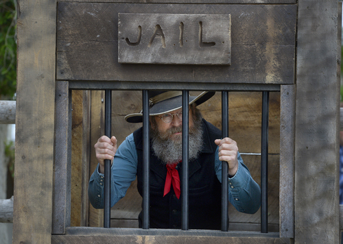 Scott Sommerdorf   |  The Salt Lake Tribune
Tony Messerly playfully sits in "jail" after he was captured during a mock arrest at the 10th Annual Cowboy Poetry and Western Music Festival at the Fielding Garr Ranch at Antelope Island State Park, Saturday, May 24, 2014.
