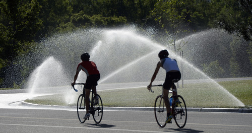 Al Hartmann  |  The Salt Lake Tribune
Bicylists take a spin around Sugar House Park early Monday morning June 9, 2014, as sprinklers  water the grass for the upcoming week when temperatures should break into the 90's.