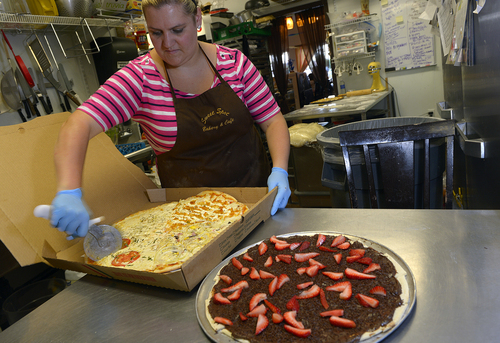 Scott Sommerdorf   |  The Salt Lake Tribune
Perola Drogueti slices a combination pizza alongside a dessert pizza with chocolate and strawberries at the  Sweet Spot Bakery and Cafe, Friday, June 13, 2014.