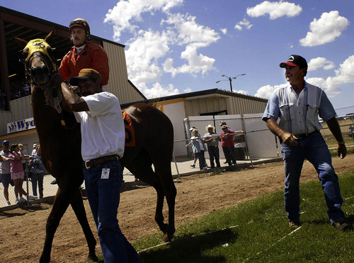 Joshua Brown  |  Tribune file photo
Lee Giles helps Chad Giles onto his horse for the fourth race of the day on the horse Willie Digs Dirt.  8/10/03