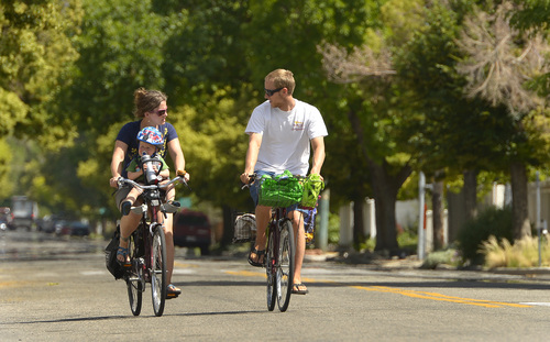 Leah Hogsten  |  The Salt Lake Tribune
"It's the slow, quiet road," said Rachel Clothier of 600 East while riding with her son Stanley, 22 months, and husband Radley Clothier, Wednesday, June 25, 2014. The couple ride their bikes along 600 East every day to the grocery, the park, the zoo and simply just for exercise. Salt Lake City is proposing to create a Bicycle Boulevard on 600 East from South Temple to 2700 South that would implement a slower speed limit and longer signals to make it easier and safer for people to bike on the road.