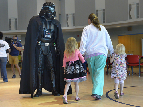 Scott Sommerdorf   |  The Salt Lake Tribune
Sisters Jenna, left, and Brooklyn Hullinger steer clear of Darth Vader (Jared Peters) as they head over to see Princesses Ariel and Snow White as costumed characters visited children at Shriner's Hospital, Thursday, June 25, 2014. The visit is in preparation for FantasyCon's "Night of Dreams" - a special preview event only July 2 for families associated with eight local charities that serve special needs and critically ill children.
