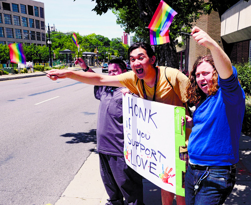 Al Hartmann  |  The Salt Lake Tribune 
Kyle Reese, left, Alexander Miller, and Cappy Shapiro wave rainbow flags and sign in a honk and wave in front of the Utah Pride Center in Salt Lake City Tuesday June 25 celebrating the 10th Circuit Courts ruling that states outlawing same-sex marriage are in violation of the U.S Constitution.