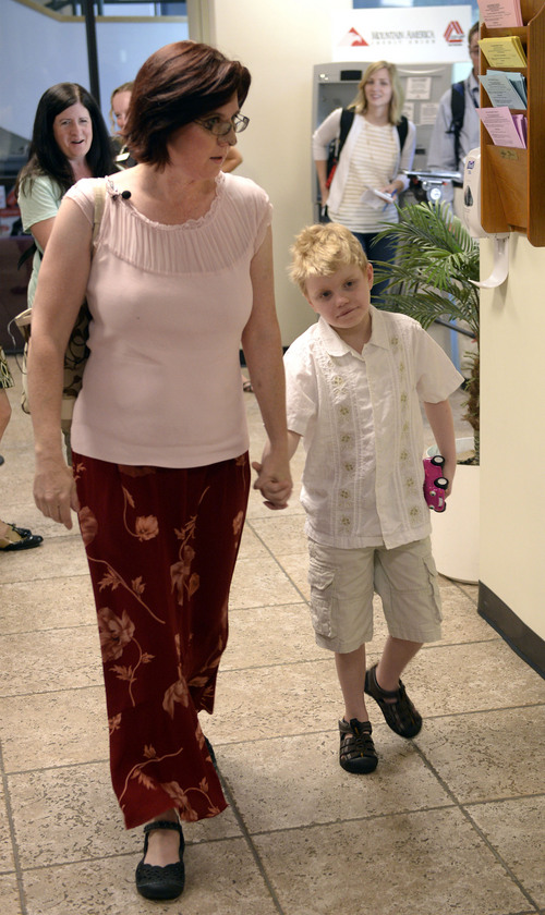 Al Hartmann  |  The Salt Lake Tribune 
Annette Maughan, her son Glenn, 11, enter the Utah Dept. of Health Tuesday July 8 to apply for a hemp extract permit, or cannabis oil permit.  Glenn has epilepsy and requires constant attention. 
The new state law allows to import the supplement from a company in Colorado called Realm of Caring. To get the permit the patient needs to prove they have intractable epilepsy -- or epilepsy that is resistant to at least three or more treatments.