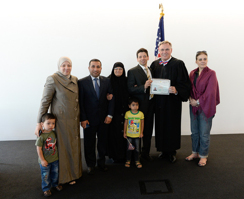 Francisco Kjolseth  |  The Salt Lake Tribune
Hussein-Jake Kadhim, center, holds his U.S. citizen certificate alongside U.S. Magistrate Judge Paul Warner as he poses for a group photo with his family on Friday, July 11, 2014. Also pictured are his sister, Noor Kadhim, lef,t and her husband, Hasan Al Rubaye and their children, Zied, 2, and Murtdah, 5, his mother, Ibtisam Salman, and Tanya Micic,  immigration coordinator for the International Rescue Committee in Salt Lake City, at right.