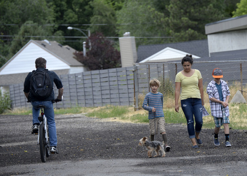 Al Hartmann  |  The Salt Lake Tribune 
Folks walk their dog and a bicyclist uses the forgotten Jordan/Salt Lake City Canal at about 1200 East and 1500 South. It appears to just be a potholed alleyway between blocks but is actually a covered canal with a 66-foot right of way that runs the length of the Salt Lake Valley at about 1100 to 1200 East. Salt Lake City has allocated more than $1 million to build a bike and pedestrian trail on top of the canal from 2700 South to 800 South. It would be called the McClelland Trail.