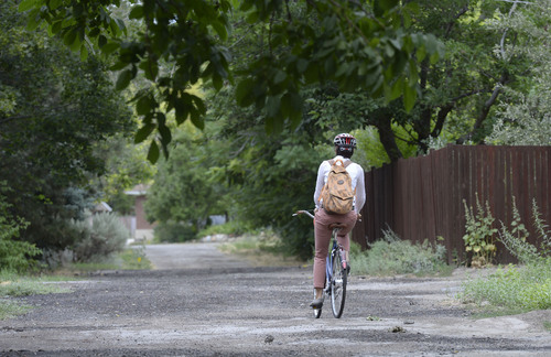 Al Hartmann  |  The Salt Lake Tribune 
Salt Lake City Councilwoman Erin Mendenhall rides along the old and forgotten Jordan/Salt Lake City Canal at about 1200 East and 1500 South. It appears to just be a potholed alleyway between blocks but is actually a covered canal with a 66-foot right of way that runs the length of the Salt Lake Valley at about 1100 to 1200 East. Salt Lake City has allocated more than $1 million to build a bike and pedestrian trail on top of the canal from 2700 South to 800 South. It would be called the McClelland Trail.