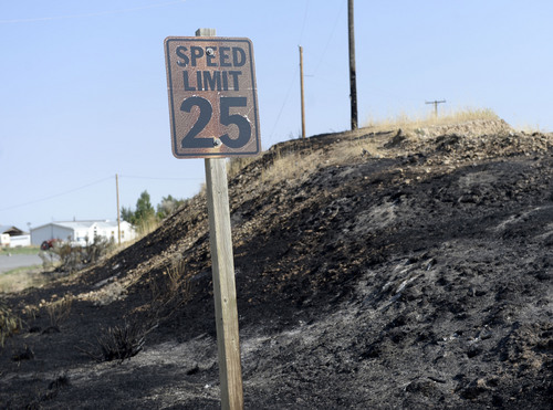 Al Hartmann  |  The Salt Lake Tribune 
A speed limit signed is burned and blistered along Copper Road.  Wild land fire fighters from several fire agencies finished mopping up the hot spots of the 179 acre fire. The town's water tank was burned in the fire necessitating a no-use water rule for part of town.
