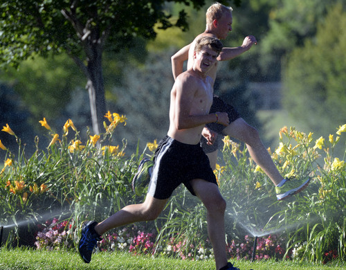 Al Hartmann  |  The Salt Lake Tribune 
Runners take advantage of sprinklers to cool down on their training run in Sugarhouse Park Monday July 21.