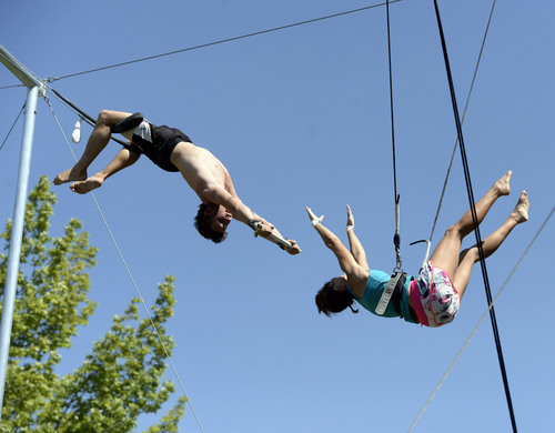 Al Hartmann  |  The Salt Lake Tribune 
Utah Flying Trapeze is open at the the south side of Pioneer Park Wednesday July 23.  Kristen Atwell of Scottsdale, AZ , right,  just misses her grab in midair by an inch from "catcher" Nick Glomb, a co-owner of the trapeze.  She had a safe controlled landing with her safety harness into the net below.  A trapeze set complete with safety harnesses, nets and instruction will be offered to the public throughout weekdays by the Utah Flying Trapeze group.
