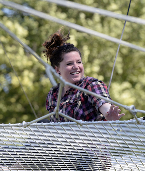 Al Hartmann  |  The Salt Lake Tribune 
Utah Flying Trapeze is open at the the south side of Pioneer Park Wednesday July 23.  Sarah Lyman of Salt Lake City, hits the net with a smile after performing a trick.  A trapeze set complete with safety harnesses, nets and instruction will be offered to the public throughout weekdays by the Utah Flying Trapeze group.