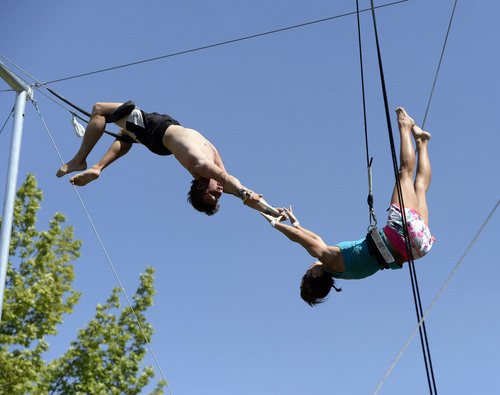 Al Hartmann  |  The Salt Lake Tribune 
Utah Flying Trapeze is open at the the south side of Pioneer Park Wednesday July 23.  Kristen Atwell of Scottsdale, AZ , right,  just misses her grab in midair by an inch from "catcher" Nick Glomb, a co-owner of the trapeze.   A trapeze set complete with safety harnesses, nets and instruction will be offered to the public throughout weekdays by the Utah Flying Trapeze group.