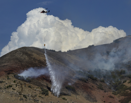 Scott Sommerdorf   |  The Salt Lake Tribune
A firefighting helicopter drops water on some remaining hotpots in the hills east of Springville, Saturday, July 26, 2014.