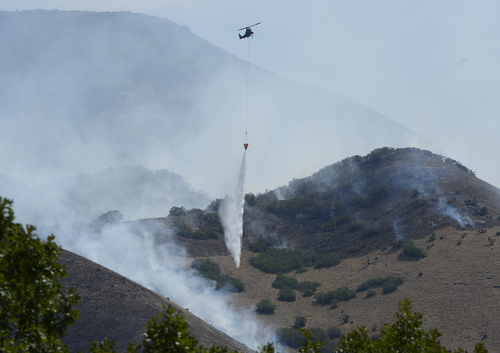 Scott Sommerdorf   |  The Salt Lake Tribune
A firefighting helicopter drops its water onto hotspots in the hills east of Springville, Saturday, July 26, 2014.