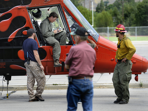 Scott Sommerdorf   |  The Salt Lake Tribune
Helicopter pilot Tyler Burrows, from Bozeman, Montana talks with ground crew as his copter is refueled at Springville High School after fighting the fire in the hills east of Springville, Saturday, July 26, 2014.