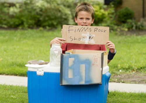 Rick Egan  |  The Salt Lake Tribune

Nine-year-old, Finn Webb, holds a sign to attract customers to his Rock Shop, in front of his home on 1900 East in Salt Lake City, Monday, July 28, 2014.  Finn's rocks range in price from 25 cents to $10.00.