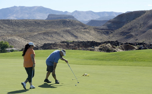 Al Hartmann  |  The Salt Lake Tribune 
Golfing in St. George during the Summer months often means playing in temperatures over 100 degrees.  Lisa and Joe Manumaleuna finish a hole at Sunbrook golf course on the part of the course with lava beds.  As if the course isn't hot enough, the black lava rocks absorb and hold in the heat. He had most of the course to himself.