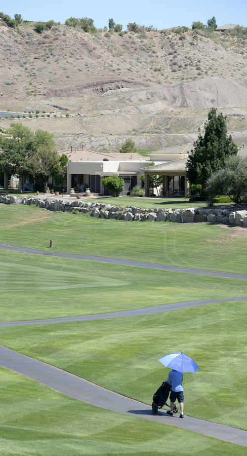 Al Hartmann  |  The Salt Lake Tribune 
Golfing in St. George during the Summer months often means playing in temperatures over 100 degrees.  Phil Kernan Jr. said that he's a slow player.  He likes not having golfers wanting to play through.  No problem here at Sunbrook Golf course Friday June 29 in the late afternoon when temperature reached 100 degrees. He has the course nearly to himself.  He wears 100 percent SPF sunblocking hat and clothing to protect himself from the sun and has an umbrella over his golf bag cart.