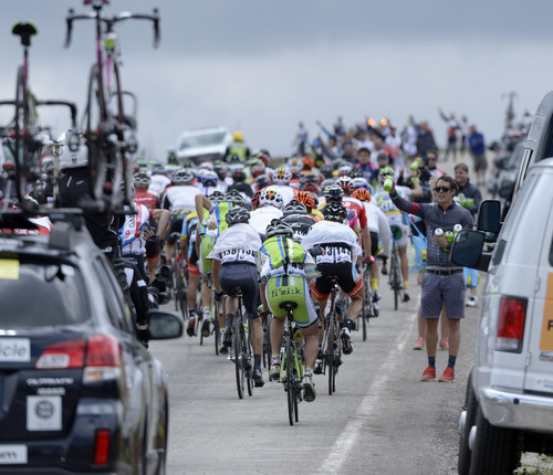 Al Hartmann  |  The Salt Lake Tribune 
The peloton clears the summit at 10,420 feet between Brian Head and Cedar Breaks National Monument Monday August 4 for the first stage of the Tour of Utah.  They grab a fresh water bottle or food as they go by. This first stage takes the riders to Parowan and up the mountain to Brian Head, past Cedar Breaks National Monument and back into Cedar City for a 113 mile race.