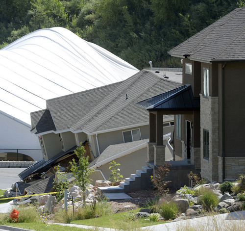 Al Hartmann  |  The Salt Lake Tribune 
A home destroyed by a  landslide at Parkway Drive in North Salt Lake. Rubble from the landslide buckles the backside of the Eagleridge Tennis dome next door.  Residents returned to their homes Wednesday Aug. 6, 2014, a day after a landslide destroyed the home and others had to be evacuated.