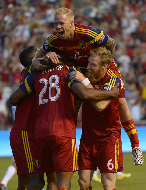 Real Salt Lake midfielder Luke Mulholland, top, forward Olmes Garcia, left, and defender Nat Borchers (6) mob defender Chris Schuler (28) after one of his two goals during the first half against D.C. United in an MLS soccer game Saturday, Aug. 9, 2014, in Sandy, Utah. (AP Photo/The Salt Lake Tribune, Leah Hogsten)