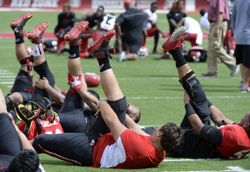 Al Hartmann  |  The Salt Lake Tribune 
Lineman stretch out hamstrings during cool down after practice at Ute football camp Wednesday August 13, 2014.