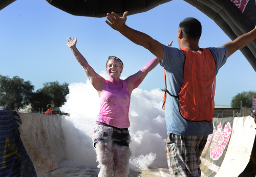 Scott Sommerdorf   |  The Salt Lake Tribune
Michelle Pecora finishes her flight of the Kiss Me Dirty Mud Run by running through a bank of soap bubbles. The run raises money for gynecological cancer research, Saturday, August 15, 2014.