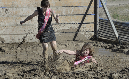 Scott Sommerdorf   |  The Salt Lake Tribune
Liz Olivares and her daughter Ruby get caught up in a mud pit during the running of the Kiss Me Dirty Mud Run. The run raises money for gynecological cancer research, Saturday, August 15, 2014.
