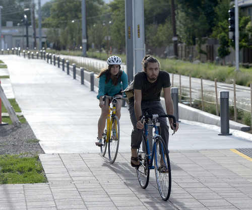Al Hartmann  |  The Salt Lake Tribune 
Bicyclists ride along the pedestrian-bike trail that runs parallel to the Sugar House streetcar line near the 500 East stop Wednesday August 13, 2014.  The steetcar is only slightly faster than the nearby parallel bus, and pedestrians sometimes can outrace it. Far fewer people than projected are riding it. And it was expensive, $37 million. But officials still see it as a success and worth the price because of the economic development it has attracted.