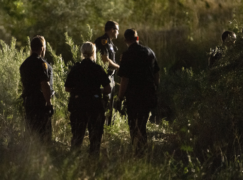 Rick Egan  |  The Salt Lake Tribune

The Salt Lake City Police wait at the river's edge as they try to coax a suspect to come out of the Jordan River, Saturday, August 23, 2014. The man jumped into the river while being pursued by the police and hung onto a branch for nearly two hours before the police were able to remove him.