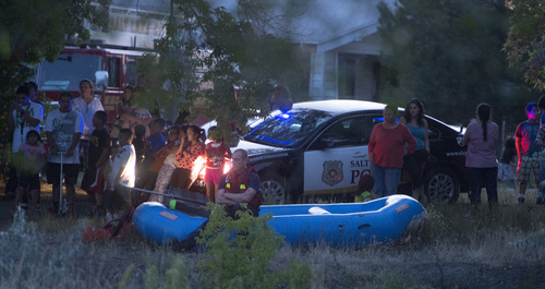 Rick Egan  |  The Salt Lake Tribune

Neighbors gather as the Salt Lake City Police try to coax a man to come out of the Jordan River, Saturday, August 23, 2014. The man jumped into the river while being pursued by the police and hung onto a branch for nearly two hours before the police were able to remove him.