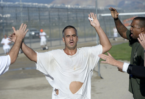 Al Hartmann  |  The Salt Lake Tribune
An exhausted inmate in the Con-Quest substance abuse program runs across the finish line and collects high fives in the first 5K race at the Utah State Prison Thursday August 28, 2014.  They ran 16 laps around the fenced jogging track made muddy from recent rain.  The 5K was a first for most inmates, who have been training in anticipation of the race and in line with the prison's Addict II Athlete program.