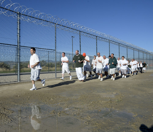 Al Hartmann  |  The Salt Lake Tribune
Con-Quest inmate Randy K Dean, left, finally jogs across the finish line in last place but backed up and encouraged by the other 43 runners in the first 5K race at the Utah State Prison Thursday August 28, 2014.  Dean said that he has a degenerative muscle disease and considers finishing the race a huge accomplishment.  Forty-three inmates ran 16 laps around the fenced jogging track made muddy from recent rain.  The 5K was a first for most inmates, who have been training in anticipation of the race and in line with the prison's Addict II Athlete program.