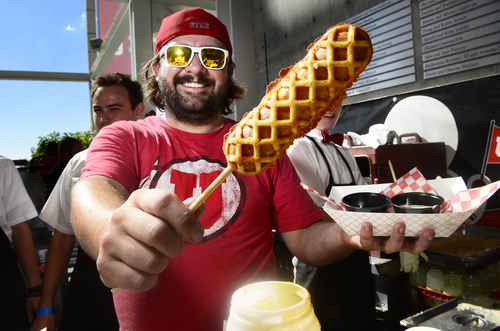 Scott Sommerdorf   |  The Salt Lake Tribune
Mike Law, one of the co-owners of the Saturday's Waffle Food Truck, proudly displays its chicken and waffle on a stick at their booth on the concourse at Rice Eccles Stadium, Thursday, Aug. 28, 2014. Their creation is the official food of the 2014 Utah State Fair. It  kind of looks like a waffle corn dog that you dip in maple syrup or gravy.