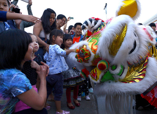 Leah Hogsten  |  The Salt Lake Tribune
Hui Shao (center)watches as her daughter Sarina Jin and friend Sunny Gao pet the lion during the Lion Dance. The  dance is meant to expel evil spirits and attract good luck for the coming year.  Salt Lake City's Chinatown Market celebrated is inaugural Moon Festival that featured Lion Dances performed by Sil Lum Kung Fu Kwoon, fireworks and martial art performances, September 5, 2014.