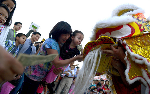 Leah Hogsten  |  The Salt Lake Tribune
Ying Luo tries to coax her daughter Alice to give the lion  $1 in honor of the performers. The lion dance is meant to expel evil spirits and attract good luck for the coming year.  Salt Lake City's Chinatown Market celebrated is inaugural Moon Festival that featured Lion Dances performed by Sil Lum Kung Fu Kwoon, fireworks and martial art performances on Friday.