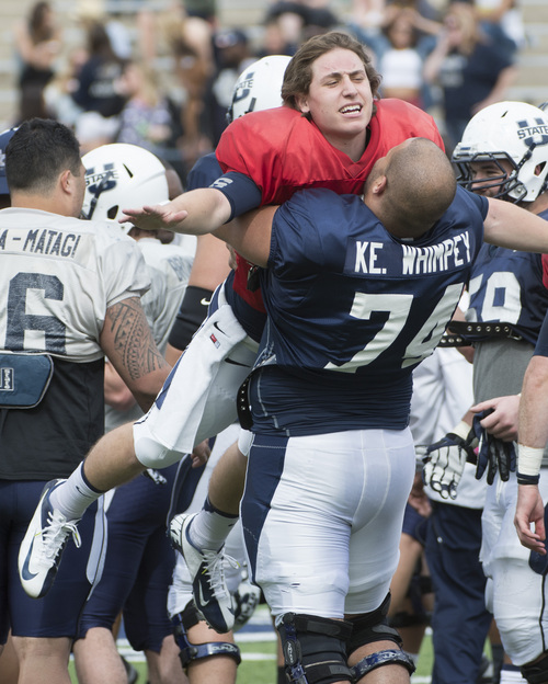 Rick Egan  |  The Salt Lake Tribune

Kevin Whimpey (74) hugs Quarterback, Darell Garretson (6) after the Utah State Aggie's final spring scrimmage, Saturday, April 12, 2014