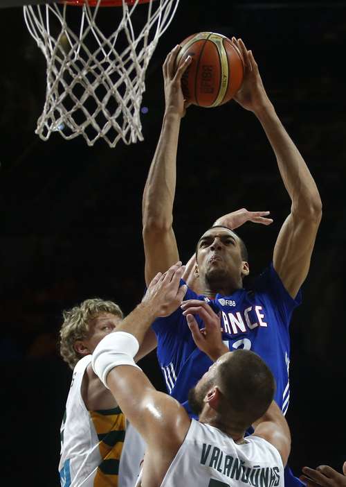 France's Rudy Gobert pushes the ball up the basket against Lithuania's Jonas Valanciunas  and Mindaugas Kuzminskas, left, during the 3rd place final of the World Basketball between France and Lithuania at the Palacio de los Deportes stadium in Madrid, Spain, Saturday, Sept. 13, 2014. (AP Photo/Andres Kudacki)
