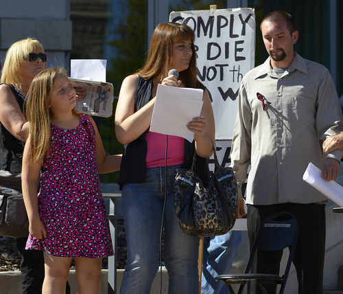 Leah Hogsten  |  The Salt Lake Tribune
l-r Baylee Archuletta, 9, and her mother Lori Archuletta look to Lori's son Brian Harris who was unarmed and shot in the head and left arm by a Layton Police officer in March of 2012 at the Families Speak Out On Police Violence rally Saturday, October 4, 2014, at the Matheson Courthouse. Brian Harris said he still had questions. "Why was I shot?" asked Harris. "What was the reason?"