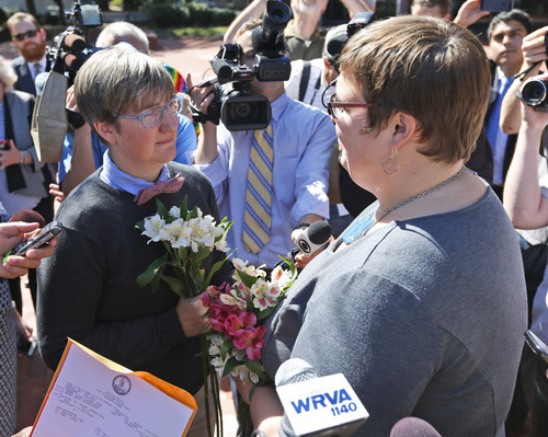 Nicole Pries, left, and Lindsey Oliver exchange vows Monday, Oct. 6, 2014, as the couple become one of the first same-sex couples in Virginia to be married,  outside a Richmond Court building in Richmond, Va. The couple were the first in the Richmond are to be married after the US Supreme Court refused to overturn same-sex marriage prohibitions. (AP Photo/Steve Helber)
