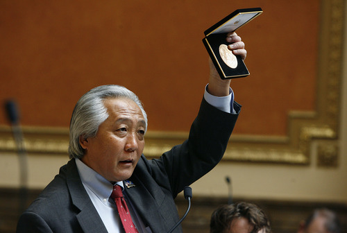 Scott Sommerdorf  |  The Salt Lake Tribune             
Rep. Curt Oda, R-Clearfield, holds aloft in the Utah House a replica of the Congressional Gold Medal that was officially presented to the 100th, the 442nd, and the MIS, including the Utah Nisei veterans, and their representatives by congressional leaders.