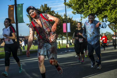 Chris Detrick  |  The Salt Lake Tribune
Zombies Cameron Romine, of Eagle Mountain, and Tyler Lloyd, of South Jordan, chase down humans during the Dawn of the Running Dead 5K race at the Utah State Fairpark Saturday October 18, 2014.