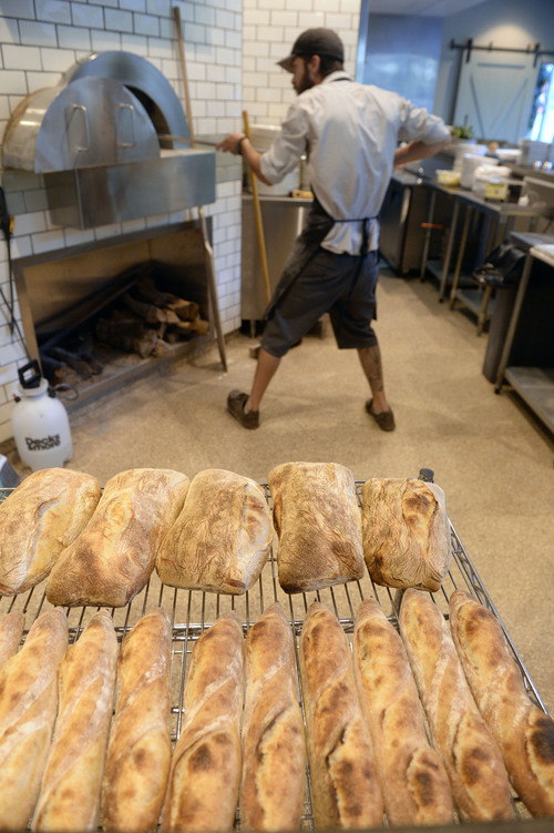 Al Hartmann  |  The Salt Lake Tribune
Ryan Moore, bread baker at From Scratch, removes hot ciabata loaves from the wood-fired pizza oven. The restaurant is the only one in the Salt Lake Valley that grinds its own wheat on-site and sells bread baked from the hearth oven. Moore is one of 15 bakers selected to try out for a spot on the Team USA culinary team.