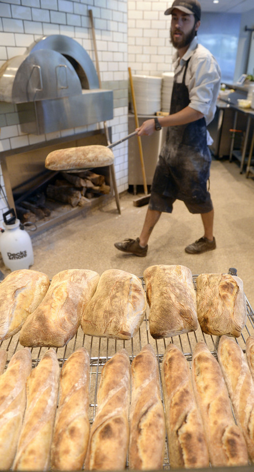 Al Hartmann  |  The Salt Lake Tribune
Ryan Moore, bread baker at From Scratch, removes hot ciabata loaves from the wood-fired pizza oven.  The restaurant is the only one in the Salt Lake Valley that grinds its own wheat on-site and sells bread baked from the hearth oven. Moore is one of 15 bakers selected to try out for a spot on the Team USA culinary team.