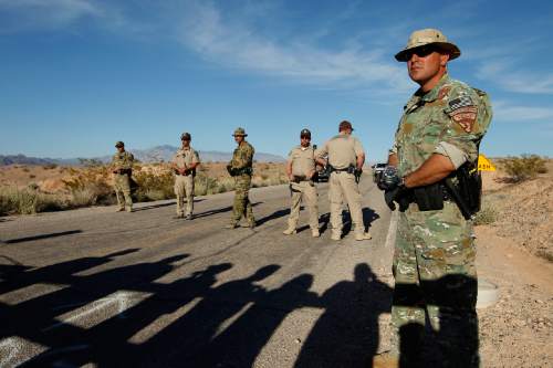 Federal law enforcement officers block a road at the Lake Mead National Recreation Area near Overton, Nev. April 10, 2014. In the foreground are the shadows of people protesting the Bureau of Land Management roundup of cattle owned by Cliven Bundy.  Former BLM director Bob Abbey says Bundy supporters who threatened BLM employees during the roundup should be held accountable. (AP Photo/Las Vegas Review-Journal, John Locher)