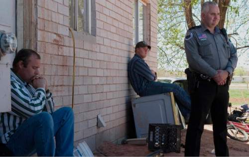Taylor Bistline occupys the doorway of a disputed home in an effort to prevent his brother, Patrick Pipkin, (not pictured) from entering while their brother Wendell Pipkin and Colorado City Police Officer Helaman Barlow await the arrival of Attorney Jeff Sheilds on Thursday morning.