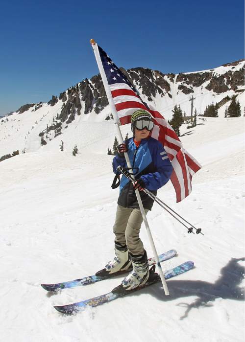 FILE - In this May 26, 2014, file photo, Carter Budge, 11, of Sandy, Utah, skis with a flag during the Snowbird Ski Resort's final day of skiing and riding for the 2013/14 winter season, in Little Cottonwood Canyon in the Wasatch Range, outside of Salt Lake City. A Colorado ski resort is settling a legal fight with Salt Lake City over winter sports marketing slogans. Steamboat Ski Resort sued in October, claiming a $1.8 million Utah advertising campaign violated its trademark on the name Ski Town, U.S.A. (AP Photo/Rick Bowmer, File)